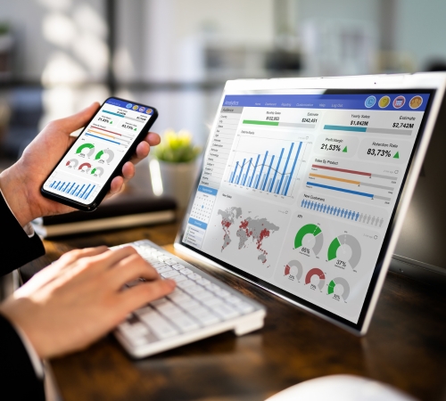 Professional analyzing real-time ERP dashboard on laptop and mobile using Green Lines system to unify operations and reduce chaos.