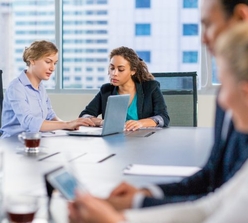 Young business people sitting in modern office and working on laptop and tablet computer. Teamwork concept